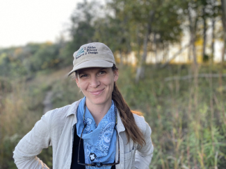 Sadie smiling for a picture on a bluff prairie at sunset.